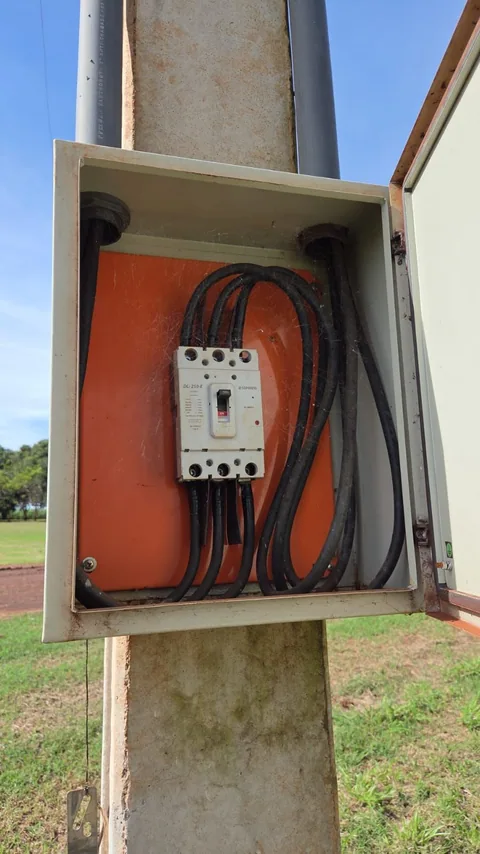 Caixa elétrica aberta em poste com cabos e dispositivo de comando