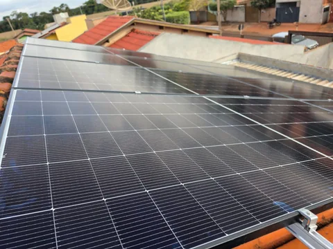 Detalhe de painéis solares em cobertura com edificações ao redor
